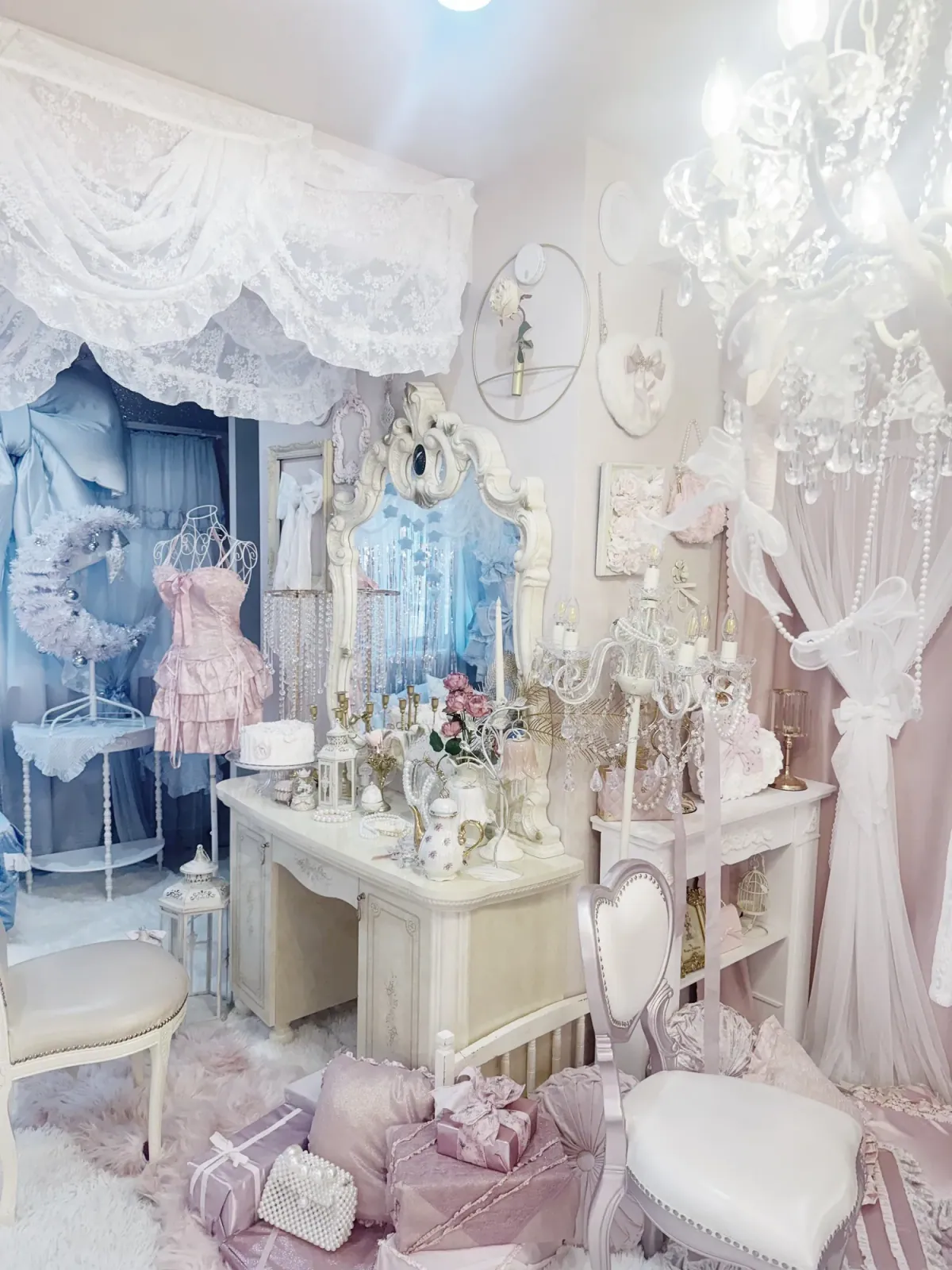 白の姫系ドレッサーにティーセットやケーキを飾ったかわいい撮影スペース。ピンクのフリルドレスやシャンデリア、月形リースも並ぶ