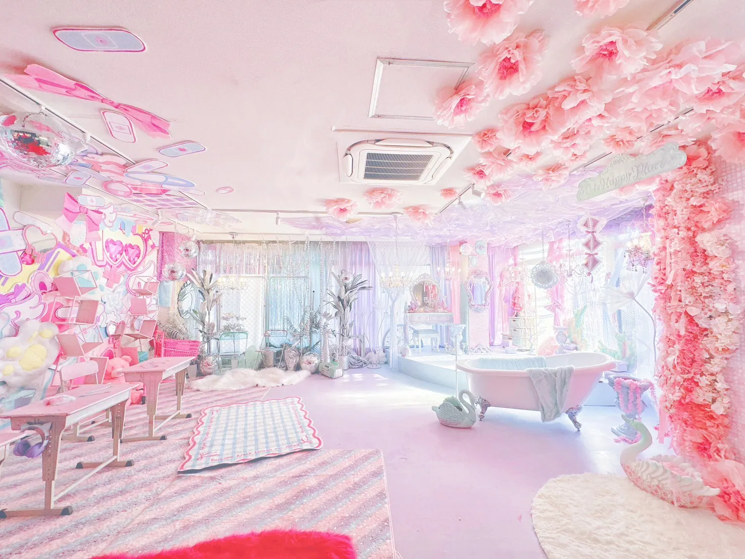 天井いっぱいのピンクの花飾りとミラーボールが輝く撮影スタジオの全景。猫足バスタブや白鳥のオブジェ、奥にドレッサーも見えるかわいい空間